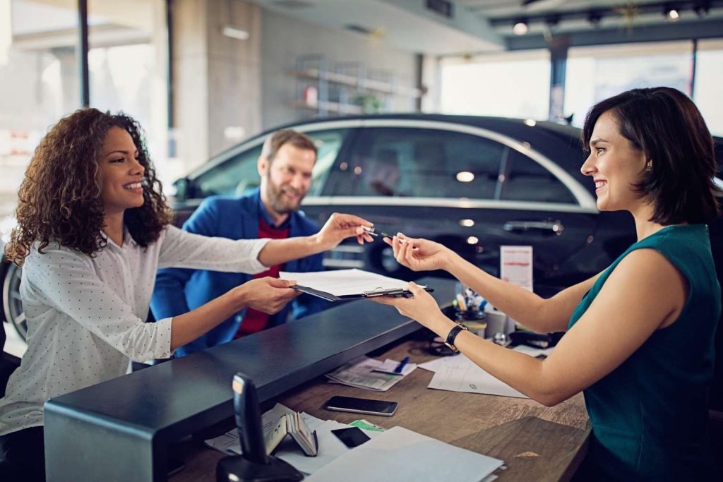 A woman being handed keys in a dealership after deciding if she was leasing or financing
